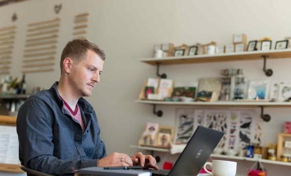 Hamline Student looking to a laptop in a coffee shop